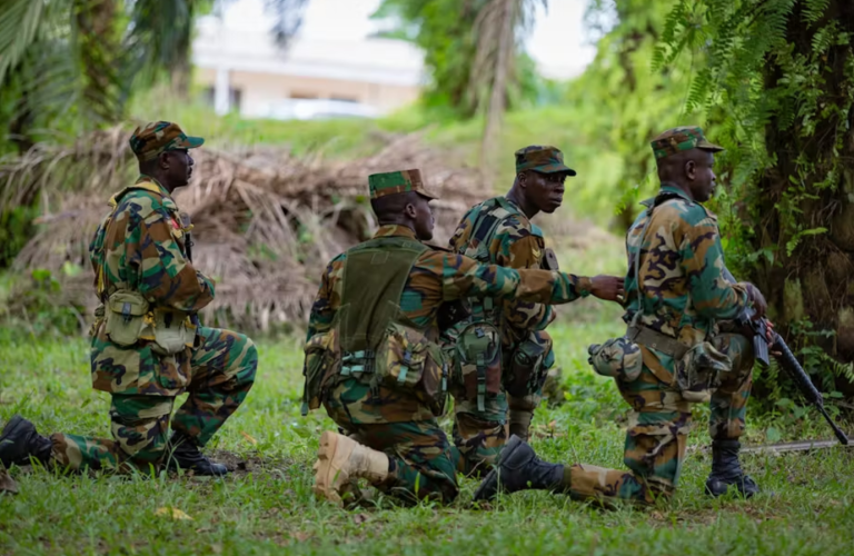 Four soldiers crouching in a forest.